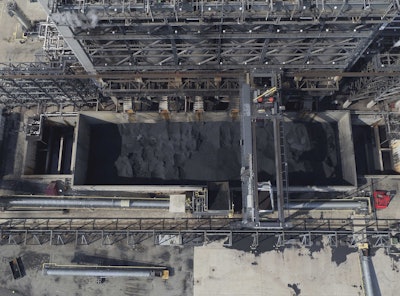 In this Sept. 21, 2017 photo, petroleum coke, the grainy black byproduct of refining Canadian tar sands oil, is visible at the BP Whiting refinery in East Chicago, Ind. The U.S. is the world's largest producer and exporter of 'petcoke,' with the largest share being shipped to India in recent years. The high-carbon, high-sulfur fuel is dirtier than coal, and has been burned unregulated in Indian factories and power plants, contributing to that nation's already-high air pollution levels. (DroneBase via AP)