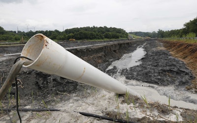 A drain pipe sticks out of a coal ash retention pond at the Dominion Power's Possum Point Power Station in Dumfries, Va. A new report released Friday, Dec. 1, 2017, from Dominion Energy says it would be cheaper and quicker to close and cover coal ash ponds than to recycle the waste or move it to landfills. (AP Photo/Steve Helber, File)