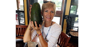 In this Nov. 28, 2017 photo, Pamela Wang poses for a photo in Kealakekua, Hawaii, with an avocado she found while on a walk. Wang is waiting to hear back from Guinness World Records to find out if the 5-pound (2.3-kilogram) avocado she snagged is the world's largest. (AP Photo/Mary Lou Knurek)
