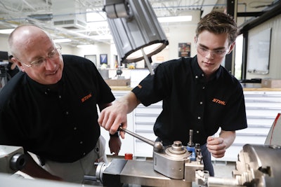 Apprentice Ryan Buzzy, 18, right, works with Skip Johnson, left, a trainer for the Stihl Inc. apprenticeship program, on a metalworking lathe in their training area at the Stihl Inc. manufacturing facility in Virginia Beach, Va. Buzzy is being trained as a “mechatronics technician” at Stihl, which makes chain saws, leaf blowers and weed trimmers at its factory in Virginia. (AP Photo/John Minchillo)