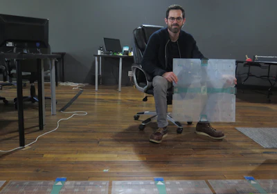 In this photo taken Dec. 5, 2017, Scanalytics co-founder and CEO Joe Scanlin holds a smart floor sensor his company creates that track people's movements in Milwaukee. The sensors are among the tools retailers are using to gain insights on consumer habits. (AP Photo/Ivan Moreno)