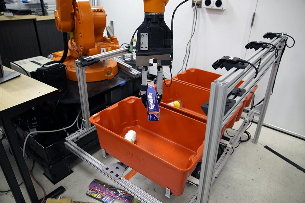 The 'pick-and-place' system consists of a standard industrial robotic arm that the researchers outfitted with a custom gripper and suction cup. They developed an 'object-agnostic' grasping algorithm that enables the robot to assess a bin of random objects and determine the best way to grip or suction onto an item amid the clutter, without having to know anything about the object before picking it up. Image credit: Melanie Gonick/MIT