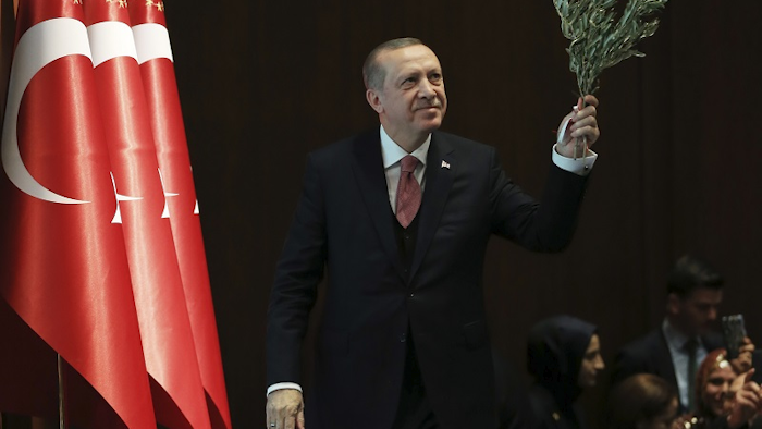 Turkey's President Recep Tayyip Erdogan, holding an olive branch arrives to deliver a speech at an event in Ankara, Turkey, Tuesday, Feb. 20, 2018. Erdogan said Turkish troops involved in the month-long offensive, codenamed 'Operation Olive Branch', to drive out Syrian Kurdish militiamen from a northwestern Syrian enclave will soon begin a siege of the city of Afrin. Image credit: Pool Photo via AP