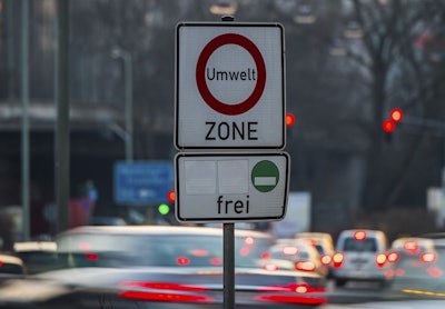 Cars pass by a sign reading 'environment zone' and allowing entrance just for cars with low emissions recognizable on a green sticker in Frankfurt, Germany, Thursday, Feb. 22, 2018. Image credit: Andreas Arnold/dpa via AP