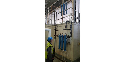 A facility supervisor inspects a cyclone separator on a compressed air system, followed by two coalescing filters. A duplicate set of filters (near ceiling) allows one set to be off-line for cleaning and maintenance, while the process line still functions.