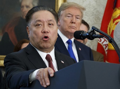 In this Thursday, Nov. 2, 2017, file photo, Broadcom CEO Hock Tan speaks while U.S. President Donald Trump listens, in background, during an event at the White House in Washington, to announce the company is moving its global headquarters to the United States. Image credit: AP Photo/Evan Vucci, File