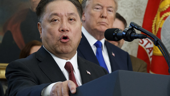 In this Thursday, Nov. 2, 2017, file photo, Broadcom CEO Hock Tan speaks while U.S. President Donald Trump listens, in background, during an event at the White House in Washington, to announce the company is moving its global headquarters to the United States. Image credit: AP Photo/Evan Vucci, File