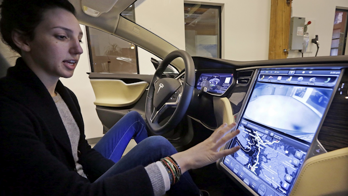 In this Feb. 4, 2015, file photo, Tesla product specialist Kat Brand explains the control panel on the electric car at a dealership for the vehicle in Seattle. Image credit: AP Photo/Elaine Thompson, File