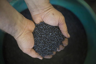 In this Tuesday, March 13, 2018 photo, a worker holds bio-based thermoplastic composite made from substantially unsorted municipal solid waste material in the UBQ factory in Kibbutz Zeelim. Israeli start-up UBQ says its innovative method to convert garbage into plastics, five years in the making, will revolutionize waste management worldwide and make landfills obsolete. (AP Photo/Ariel Schalit)