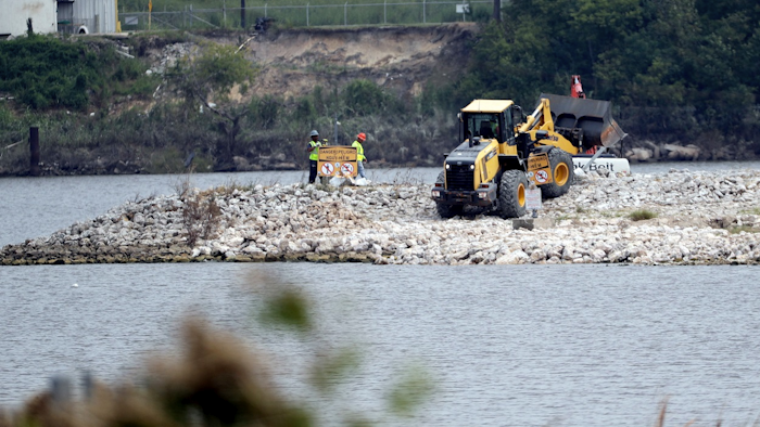 In this Sept. 13, 2017, file photo, workers are shown at San Jacinto River Waste Pits near the Interstate 10 bridge over the river in Channelview, Texas. Image credit: AP Photo/David J. Phillip, File