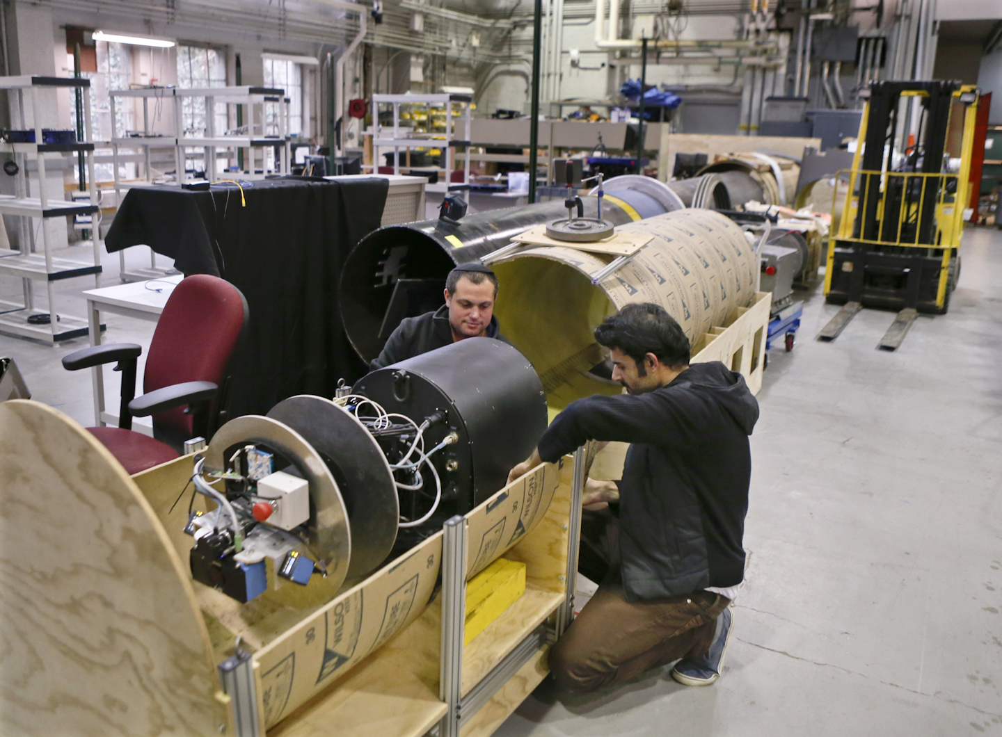In this photo made on Wednesday, April 4, 2018, David Kohandash, left, and Mohammad Mousaei work on the RadPiper robot in the robotics institute at Carnegie-Mellon University in Pittsburgh. The mechanism is designed to measure potentially hazardous radiation is intended to go through pipes at a former uranium plant being cleaned up in southern Ohio. (AP Photo/Keith Srakocic)