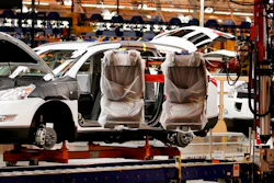 In this Oct. 3, 2008, file photo, assembly line worker Melvin Matthews, right, uses a large robotic machine to install front seats in a new 2009 Chevrolet Traverse at the GM Spring Hill Manufacturing Plant, in Spring Hill, Tenn. Image credit: AP Photo/Bill Waugh, File