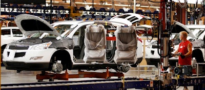 In this Oct. 3, 2008, file photo, assembly line worker Melvin Matthews, right, uses a large robotic machine to install front seats in a new 2009 Chevrolet Traverse at the GM Spring Hill Manufacturing Plant, in Spring Hill, Tenn. Image credit: AP Photo/Bill Waugh, File