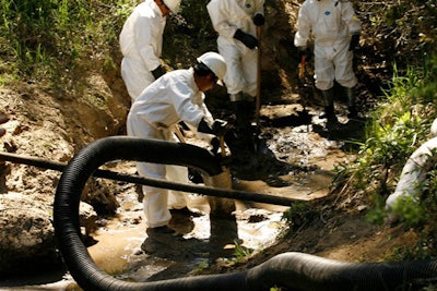 In this March 13, 2008, file ph too, workers use a guzzler vacuum to suck oil soaked sediment from a creek in Santa Maria, Calif., after oil spilled into the creek from a Greka Oil & Gas Inc. facility. The California oil company with a long history of safety violations and regulatory lapses was hit with a record $12.5 million fine by state regulators Wednesday, April 11, 2018, for nearly 1,500 violations in the past year at an oil field in Orange County. (AP Photo/Damian Dovarganes, File)
