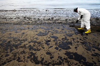 In this May 21, 2015, file photo, a worker removes oil from sand at Refugio State Beach, north of Goleta, Calif. Jurors being selected Thursday, April 19, 2018, in Santa Barbara County Superior Court will determine if Plains All American Pipeline, a Texas company that operated an oil pipeline that spilled crude along the California three years ago, broke any laws. (AP Photo/Jae C. Hong, File)