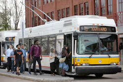 In this Wednesday, May 2, 2018 photo passengers board a bus powered by electricity supplied through overhead wires, in Watertown, Mass. Image credit: AP Photo/Steven Senne