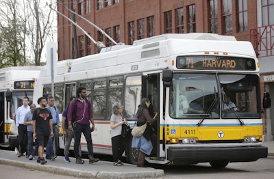 In this Wednesday, May 2, 2018 photo passengers board a bus powered by electricity supplied through overhead wires, in Watertown, Mass. Image credit: AP Photo/Steven Senne