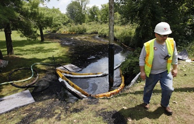 In this July 29, 2010, file photo, a worker monitors the water in Talmadge Creek in Marshall Township, Mich., near the Kalamazoo River as oil from a ruptured pipeline, owned by Enbridge Inc, is vacuumed out of the water.Image credit: AP Photo/Paul Sancya, File
