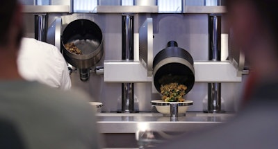 Customers wait as their automatically prepared food is dropped from a cooking pot into a bowl at Spyce, a restaurant which uses a robotic cooking process in Boston, Thursday, May 3, 2018. Image credit: AP Photo/Charles Krupa