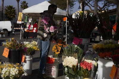 In this Thursday, April 12, 2018, photo, a man buys locally grown flowers at a farmers' market in Carpinteria, Calif. Image credit: AP Photo/Jae C. Hong