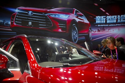 In this April 25, 2018, file photo, attendees look at the Tang SUV by Chinese automaker BYD after a press conference at the China Auto Show in Beijing. Image credit: AP Photo/Mark Schiefelbein, File