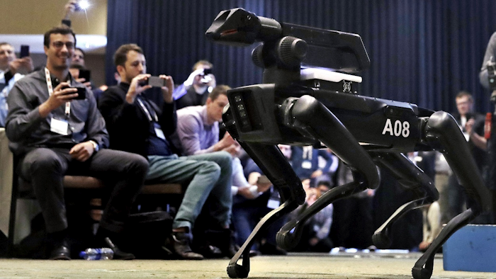 In this Thursday, May 24, 2018, photo, a Boston Dynamics SpotMini robot is walks through a conference room during a robotics summit in Boston. Image credit: AP Photo/Charles Krupa