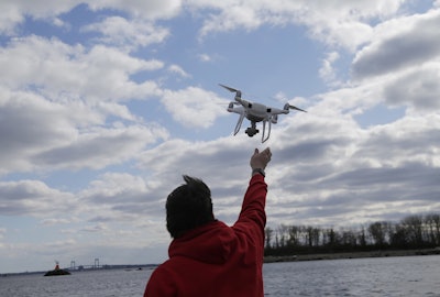 In this April 29, 2018, file photo, a drone operator helps to retrieve a drone after photographing over Hart Island in New York. Image credit: AP Photo/Seth Wenig, File