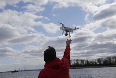 In this April 29, 2018, file photo, a drone operator helps to retrieve a drone after photographing over Hart Island in New York. Image credit: AP Photo/Seth Wenig, File