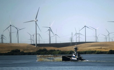 In this Sept. 23, 2013, file photo, a tugboat pushes a barge down the Sacramento River past wind turbines near Rio Vista, Calif. Image credit: AP Photo/Rich Pedroncelli, File