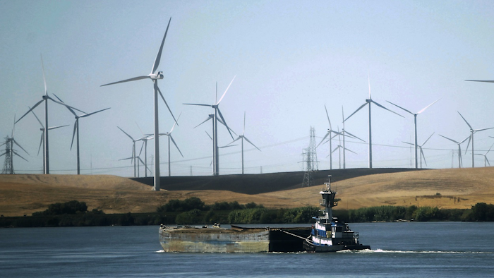 In this Sept. 23, 2013, file photo, a tugboat pushes a barge down the Sacramento River past wind turbines near Rio Vista, Calif. Image credit: AP Photo/Rich Pedroncelli, File