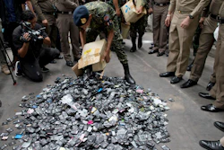 A Thai law-enforcement officer unloads a box full of mobile batteries during a raid at a factory accused of importing and processing electronic waste in the suburbs of Bangkok, Thailand on Thursday, June 21, 2018. Image credit:AP Photo/Gemunu Amarasinghe