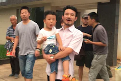 In this June 28, 2017 file image taken from video, Chinese labor activists Hua Haifeng, center, carries his son Bo Bo, and Li Zhao, second left, leave a police station after being released in Ganzhou in southern China's Jiangxi Province. Image credit: AP Photo/Gerry Shih, File