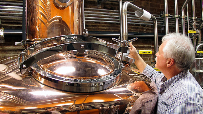 FILE - In this Wednesday Nov. 13, 2013, file photo, Charlie Downs, the artisanal craft distiller at a new Heaven Hill Distilleries, Louisville, Ky., checks gauges on a still that will produce small batches of whiskey. The whiskey industry on Friday celebrated a new state law allowing some bourbon fans to receive home deliveries, shipped straight from their favorite Kentucky distilleries. Bourbon industry leaders and state officials led by Gov. Matt Bevin participated as the first shipments were sent off for delivery.(AP Photo/Bruce Schreiner, File)