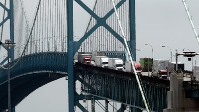 In this Tuesday, June 12, 2018, photo, trucks cross the Ambassador Bridge from Windsor, Ontario into Detroit. In nearly a quarter-century since NAFTA was approved, a complex chain of automotive parts makers has sprung up on both sides of the U.S.-Canada border. About 7,400 trucks cross the bridge between Detroit and Windsor every day, many laden with auto parts. (AP Photo/Paul Sancya)