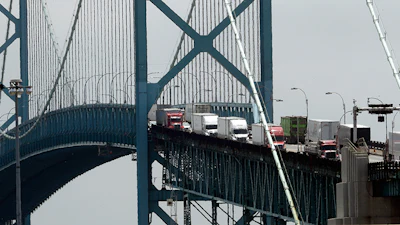 In this Tuesday, June 12, 2018, photo, trucks cross the Ambassador Bridge from Windsor, Ontario into Detroit. In nearly a quarter-century since NAFTA was approved, a complex chain of automotive parts makers has sprung up on both sides of the U.S.-Canada border. About 7,400 trucks cross the bridge between Detroit and Windsor every day, many laden with auto parts. (AP Photo/Paul Sancya)