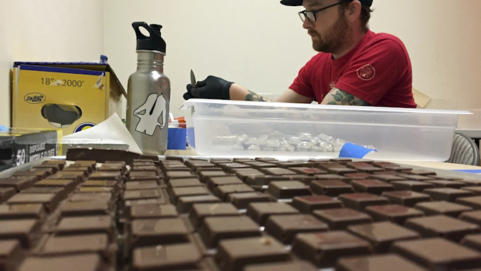 In this June 2, 2016 file photo, Chalice Farms production manager John Schuch wraps cannabis-infused hazelnut milk chocolates infused with marijuana in foil papers to prepare for sale at the company headquarters in Portland, Ore. Image credit: AP Photos/Gillian Flaccus, File