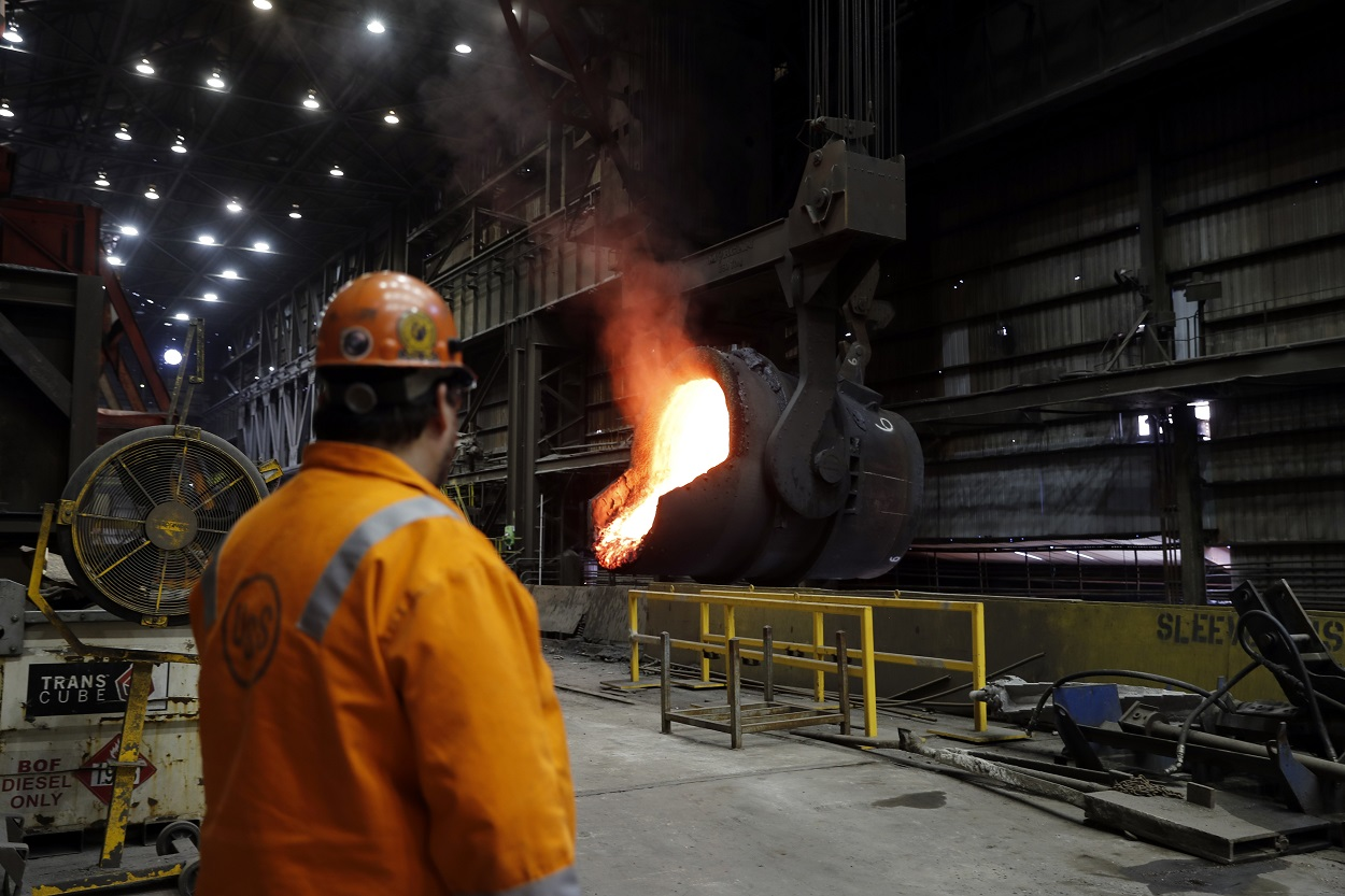 In this June 28, 2018 photo, senior melt operator Randy Feltmeyer watches a giant ladle as it backs away after pouring its contents of red-hot iron into a vessel in the basic oxygen furnace as part of the process of producing steel at the U.S. Steel Granite City Works facility in Granite City, Ill. Image credit: AP Photo/Jeff Roberson