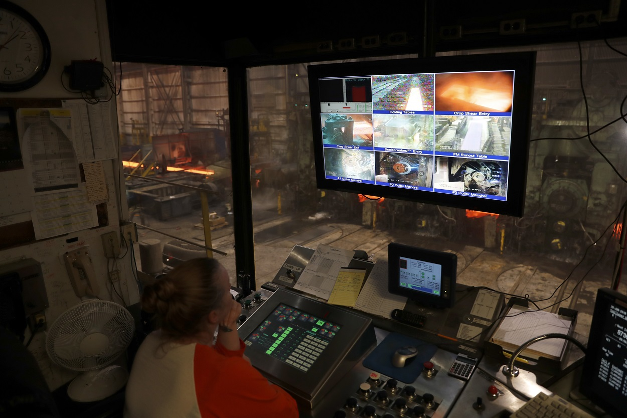 In this June 28, 2018 photo, steelworker Amanda Menendez keeps watch over various stages of the production process on monitors in an office as steel is produced on the floor below inside the hot-strip mill at the U.S. Steel Granite City Works facility in Granite City, Ill. Image credit: AP Photo/Jeff Roberson