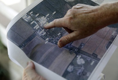 In this Thursday, June 7, 2018, photo, Kevin Butler looks at parts of a groundwater report, in Garden City, Ind. The water in the home is pumped through a water-filtration system. The collapse of Kiel Bros. Oil Co. in 2004 was widely publicized. Less known is that the state of Indiana and, to a smaller extent, Kentucky and Illinois, are still on the hook for millions of dollars to clean up more than 85 contaminated sites across the three states, including underground tanks that leaked toxic chemicals into soil, streams and wells. Indiana alone has spent at least $21 million on the cleanup thus far, or an average of about $500,000 per site, according an analysis of records by The Associated Press. (AP Photo/Darron Cummings)