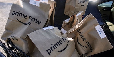FILE - In this Feb. 8, 2018, file photo, Amazon Prime Now bags full of groceries are loaded for delivery by a part-time worker outside a Whole Foods store in Cincinnati. Amazon’s Prime Day deals are coming to the aisles of Whole Foods, as the online retailer seeks to lure more people to its Prime membership after recently hiking up the price. (AP Photo/John Minchillo, File)