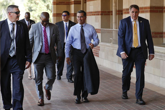 California Attorney General Xavier Becerra, center, walks on the campus of University of California, Los Angeles, Thursday, Aug. 2, 2018. Becerra spoke at a news conference about his efforts to fight the Trump administration's proposal to weaken car efficiency fuel standards. (AP Photo/Jae C. Hong)