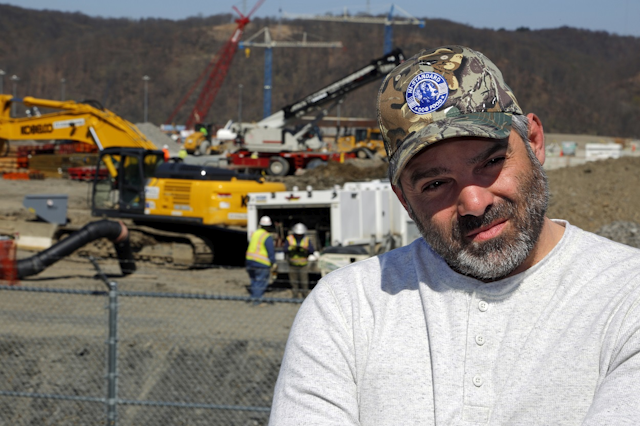 In this April 30, 2018 photo, Chip Kohser, the Beaver county Republican chairman, stands overlooking the construction of a chemical plant on the banks of the Ohio River near Beaver, Pa., that will help convert natural gas into plastic, creating hundreds of jobs in an area that has seen population dwindle since the collapse in the 1980's of the steel industry. Image credit: AP Photo/Gene J. Puskar