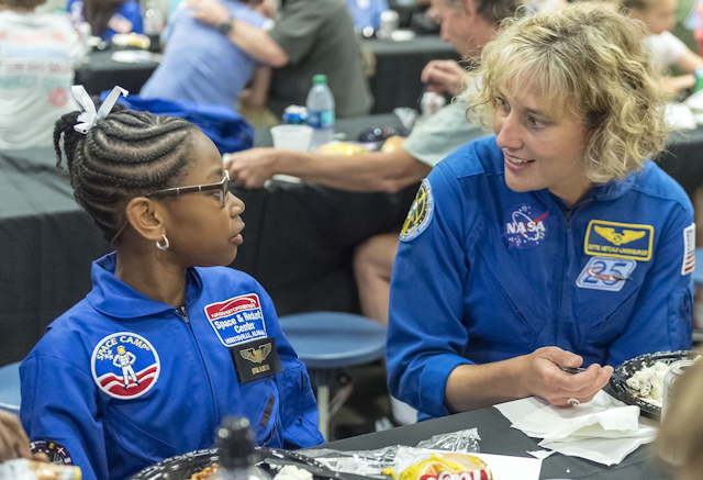 In this July 13, 2018 photo, retired designer Jim Jenkins, who volunteers to educate the next generation three days a week, talks with Whitt Harbour of Tupelo, Miss., about powering the engines of the Saturn V rocket at the U.S. Space & Rocket Center in Huntsville, Ala. Image credit: AP Photo/Vasha Hunt