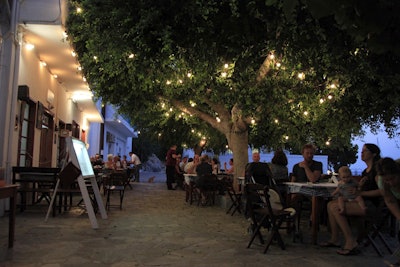 In this photo dated Monday, Aug. 6, 2018, people eat in a tavern in the Aegean island of Tilos, Greece. Image credit: AP Photo/ Iliana Mier