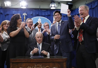 State Sen. Kevin de Leon, D-Los Angeles, right, shakes hands with Gov. Jerry Brown after Brown signed his environmental measure SB100, Monday, Sept. 10, 2018, in Sacramento, Calif. Image credit: AP Photo/Rich Pedroncelli