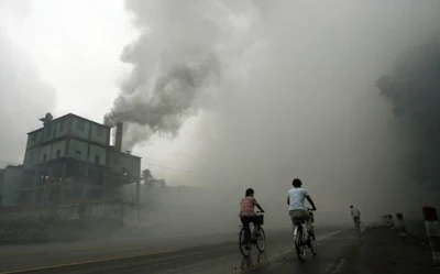 This photo taken on July 18, 2006 shows cyclists passing through thick pollution from a factory in Yutian, 100km east of Beijing in China's northwest Hebei province. Surging levels of carbon dioxide sent greenhouse gases in the atmosphere to a new record in 2013, while oceans, which absorb the emissions, have become more acidic than ever, the UN said on September 9, 2014. (AFP Photo/Peter Parks)
