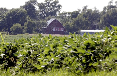 In this July 24, 2018, file photo a barn with a banner reading 'Trump' is seen behind a field of soy beans in Ashland, Neb. Image credit: AP Photo/Nati Harnik, File