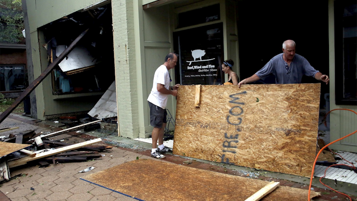 In this Sept. 15, 2018, file photo Jay Manning, left, and Shannon Corr clean up the damaged storefront of the Surf, Wind and Fire store caused by the tropical storm Florence in New Bern, N.C. Image credit: AP Photo/Chris Seward, File