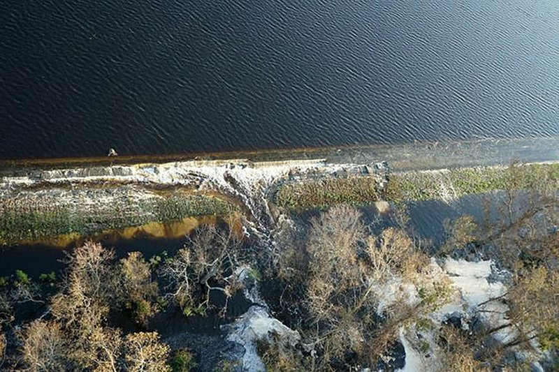 In this photo released Friday, Sept. 21, 2018, by Duke Energy, Gray material that Duke Energy characterized as lightweight coal combustion byproducts could be seen Friday floating on the top of the lake, near Wilmington, N.C. The ash left over when coal is burned to generate electricity coal ash contains an array of components, including mercury, lead, arsenic and other toxic heavy metals. The inundated basin contains at the plant 400,000 cubic yards of ash. (Duke Energy via AP)