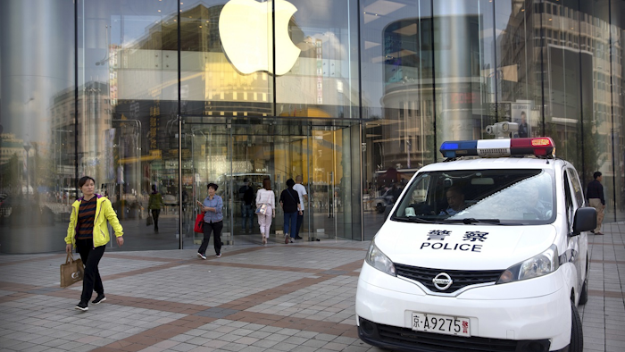 Chinese police sit in their vehicle as it is parked outside an Apple store at an outdoor shopping area in Beijing, Tuesday, Sept. 25, 2018. Image credit: AP Photo/Mark Schiefelbein